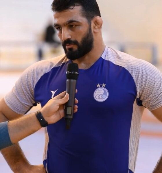 حسن یزدانی با پیراهن آبی روی تشک کشتی می‌رود